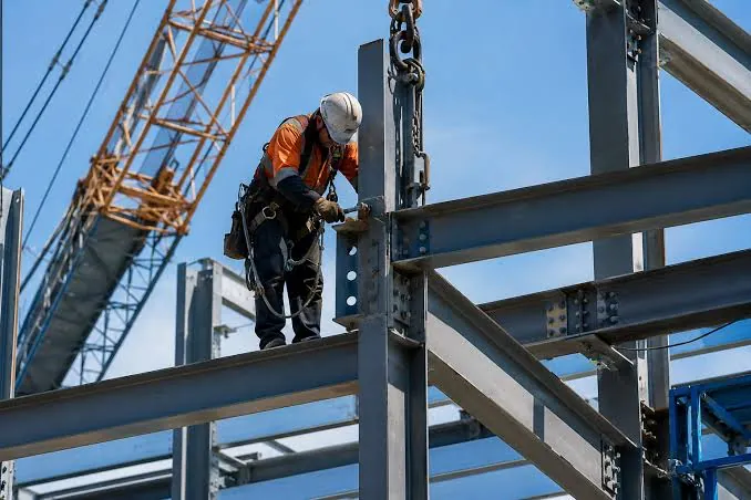 Roofer in safety gear working on a steel roof frame